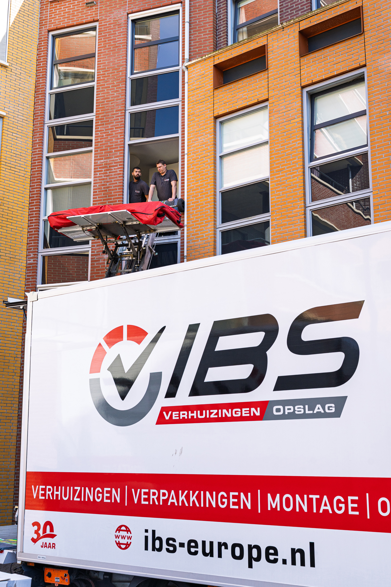 Verhuizers werken met een verhuislift bij een appartement