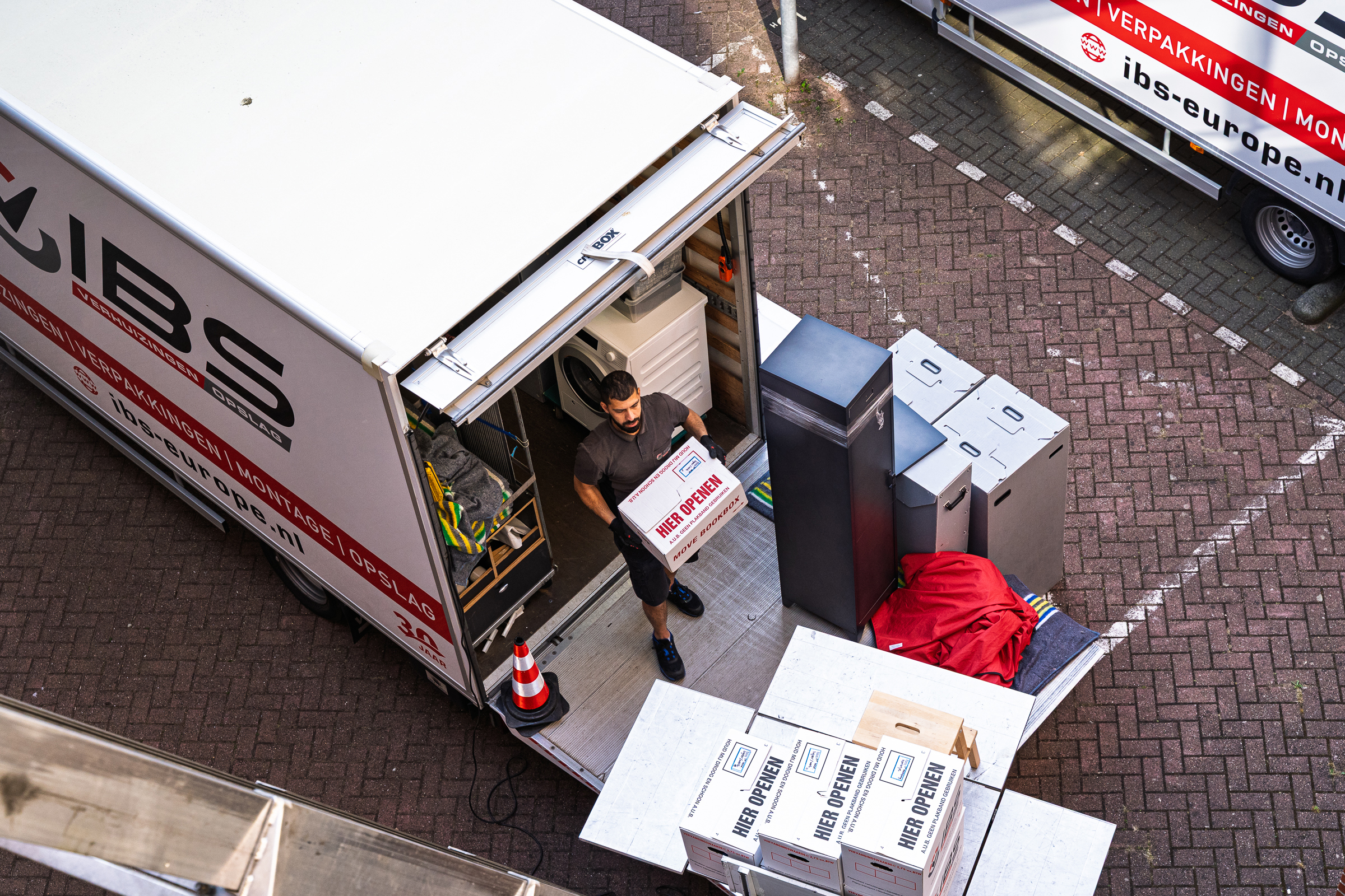Verhuizer haalt een verhuisdoos uit de verhuiswagen naast een verhuislift